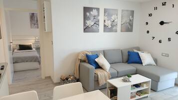 A modern living room with a grey sofa, a white coffee table, and a bookshelf.