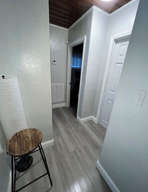 Un couloir avec un radiateur, une chaise et une porte donnant sur une autre pièce.