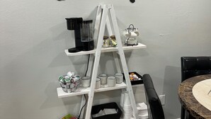 Ein Kaffee- und Tee-Bar-Bereich mit einer weißen Wendeltreppe als Regal, auf der Tassen und eine Kaffeemaschine stehen.