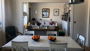 Een eetgedeelte met een marmeren tafel, stoelen en een schaal sinaasappels.