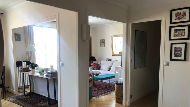 Een ruime woonkamer met houten vloer, een zithoek en een eethoek met tafel en stoelen.