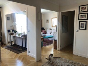 A spacious living area with a wooden floor, a sofa set, and a dining area with a table and chairs. - Very Cosy Family appartment in Paris, 5 min walk to Eiffel Tower & Invalides (Paris)