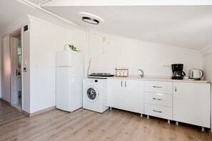 A modern kitchen with white cabinetry, a washing machine, a refrigerator, and a coffee maker. - Boutique Apartment Escape Near Taksim (Istanbul)