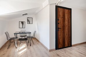 A room with a dining table, chairs, a wooden door, and two framed pictures on the wall. - City Loft Retreat Near Taksim Square (Istanbul)