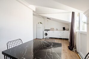 A compact kitchen with a washing machine, a coffee maker, and a dining area with a marble table. - Boutique Apartment Escape Near Taksim (Istanbul)
