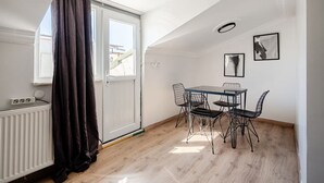 A room with a dining table and chairs, a radiator, a window with curtains, and a ceiling light fixture. - City Loft Retreat Near Taksim Square (Istanbul)