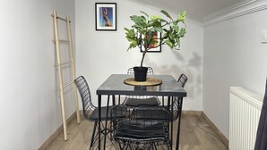 Un comedor con una mesa, sillas, una planta en maceta, una escalera y un cuadro en la pared.