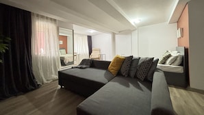 Una sala moderna con sofá, sillón y cama.