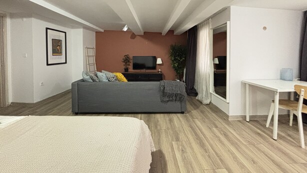 Una sala de estar moderna con sofá, televisión y escritorio.