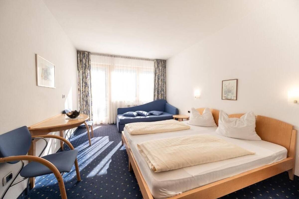 A hotel room with a bed, a sofa, a desk, and a chair.