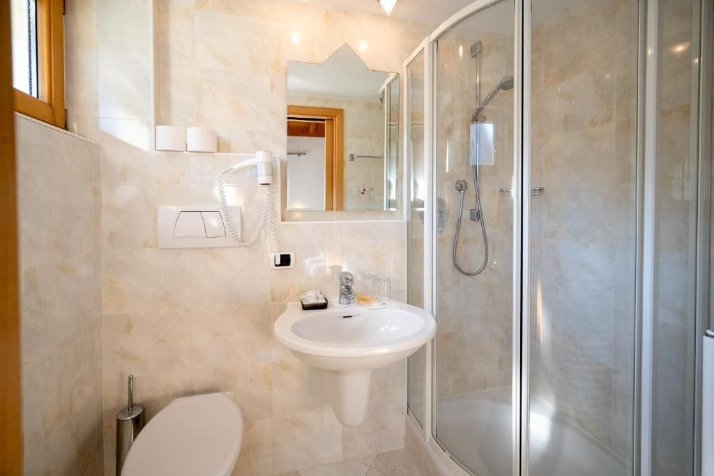 A bathroom with a glass-enclosed shower, a white sink, and a toilet.