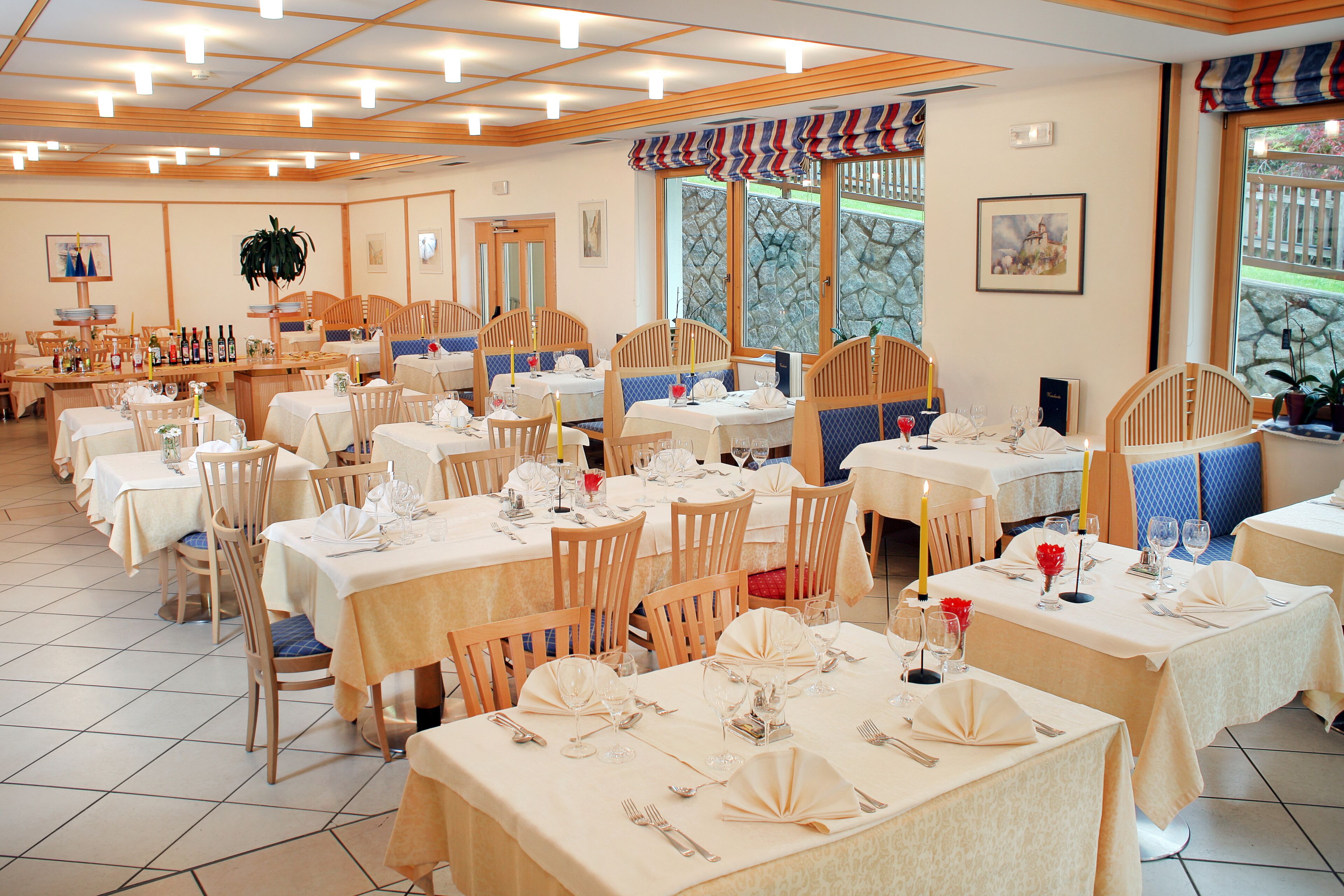 A restaurant with multiple tables, chairs, and a variety of table settings.