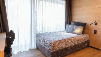 Quarto com cama grande, paredes de madeira, escrivaninha e cadeira.