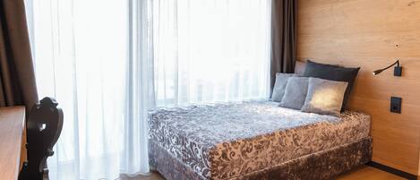 Un dormitorio con una cama grande, paredes de madera, un escritorio y una silla.