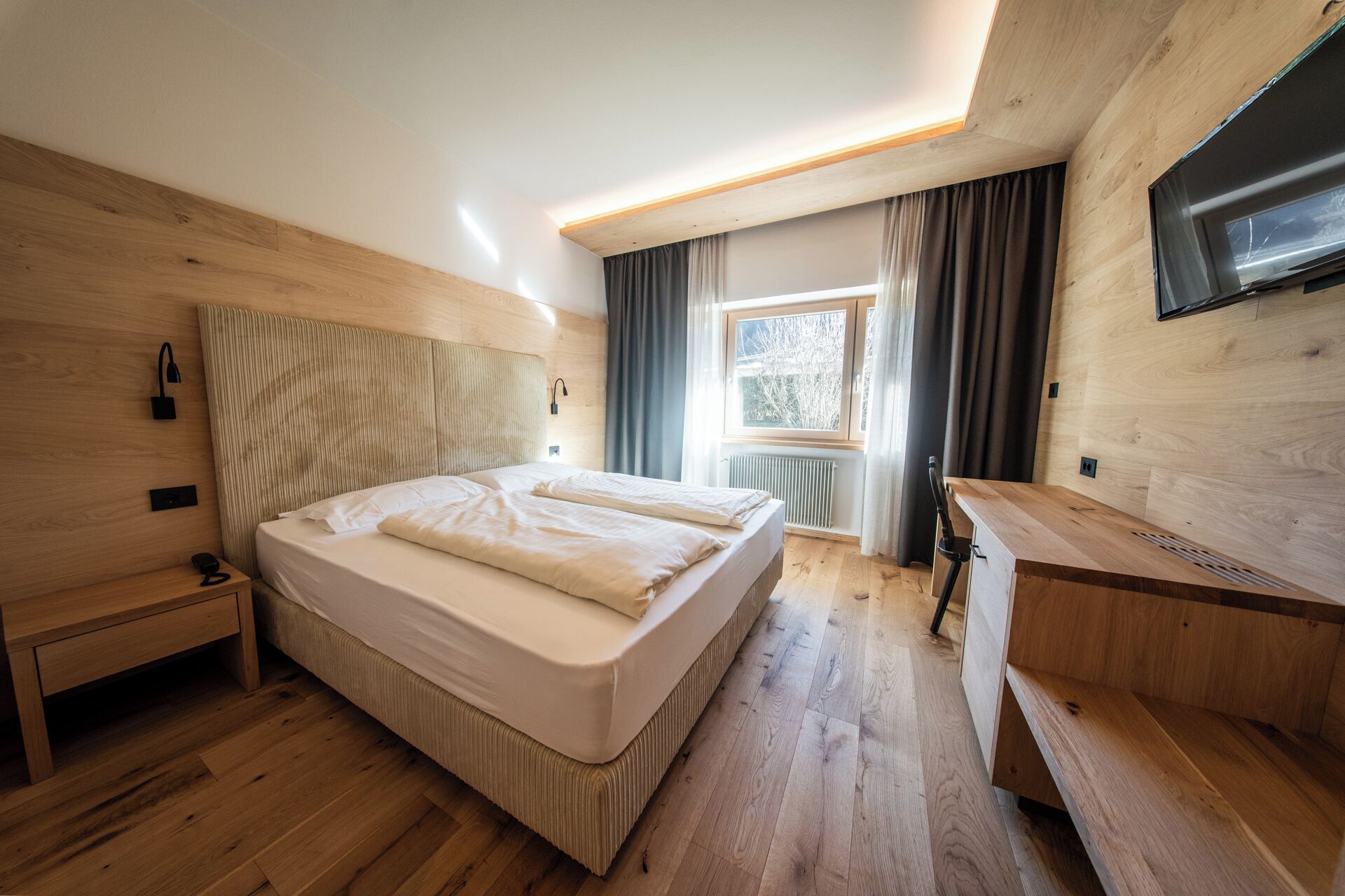 A modern bedroom with a bed, bedside table, and a desk.