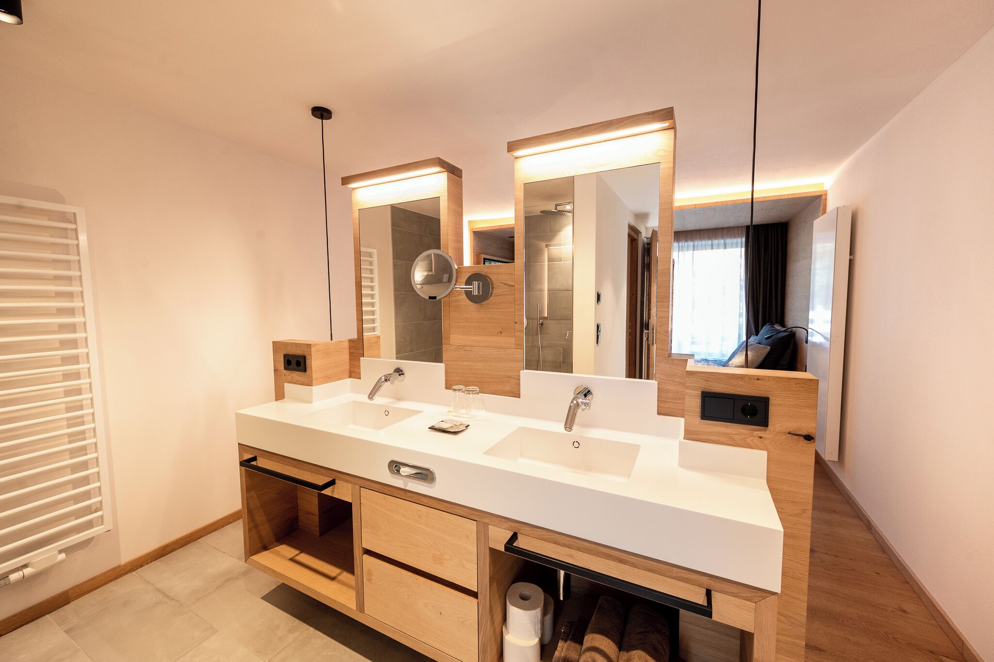 Un baño moderno con lavamanos doble, tocador de madera y espejos grandes.