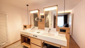 Un baño moderno con lavamanos doble, tocador de madera y espejos grandes.