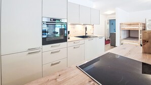 Uma cozinha moderna com armários brancos, forno embutido, pia e uma mesa de jantar de madeira.