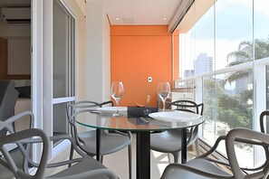 Un comedor moderno con una mesa de vidrio, sillas de metal y vistas de la ciudad a través de amplias ventanas.
