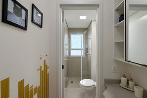 Un baño moderno con inodoro, ducha y un ventanal.