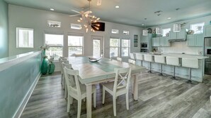 A spacious kitchen with a central island, white bar stools, and a ceiling fan. - No Plana Cabana Close to Beach (Port Aransas)