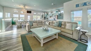 A spacious living room with a sofa, coffee table, and a dining area with chairs. - No Plana Cabana Close to Beach (Port Aransas)