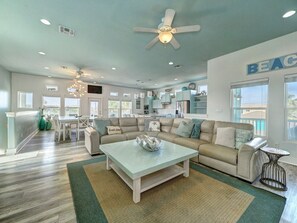 A spacious living room with a sofa, coffee table, and a dining area with chairs. - No Plana Cabana Close to Beach (Port Aransas)