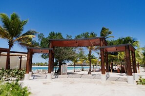 A beachside resort with wooden gazebos, palm trees, and a clear view of the ocean. - Villa de lujo totalmente equipada en Vista Cana a minutos del centro (Punta Cana)