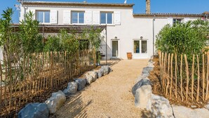 Un sentiero che conduce a un edificio con facciata bianca, diverse finestre e un portone.