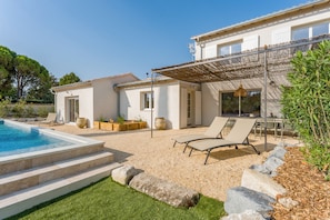 A modern villa with a swimming pool, outdoor seating, and a pergola.