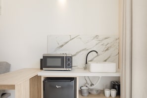 Eine kleine Küchenzeile mit Mikrowelle, Spüle und integriertem Kühlschrank.