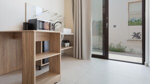 A modern room with a wooden cabinet, a white sink, and a sliding glass door leading to an outdoor area with a view of a building and a statue. - Artemis Studio Apartment in Laganas, Zante with Sea Activities (Laganas)