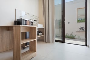 Ein modernes Zimmer mit einem Holzschrank, einem weißen Waschbecken und einer Glastür, die zu einem Außenbereich mit Blick auf ein Gebäude und eine Statue führt.