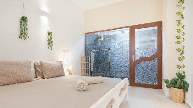 A bedroom with a bed, a wooden ladder, and a door leading to a bathroom. - Artemis Studio Apartment in Laganas, Zante with Sea Activities (Laganas)