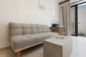 A modern living room with a sofa, a coffee table, a TV, and a sliding glass door leading to an outdoor area. - Artemis Studio Apartment in Laganas, Zante with Sea Activities (Laganas)