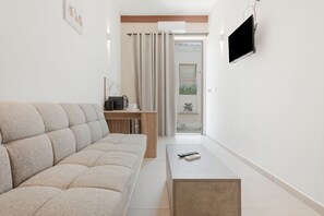 Ein modernes Wohnzimmer mit einer Couch, einem Couchtisch, einem Fernseher und einer Schiebetür, die auf einen Balkon führt.