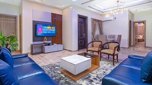 A modern living room with a flat-screen TV, leather sofas, a coffee table, and a dining area. - Poise And Class Apartment (Lagos)