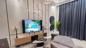 A modern living room with a flat-screen TV, a sofa, a coffee table, and a decorative plant. - Poise And Class Apartment (Lagos)