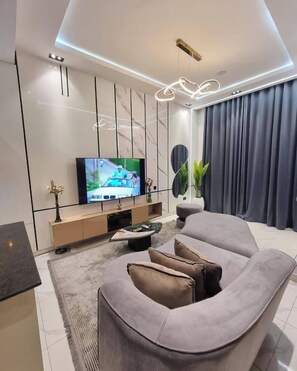 Una sala de estar moderna con un televisor de pantalla plana, un sofá, una mesa de centro y una planta decorativa.