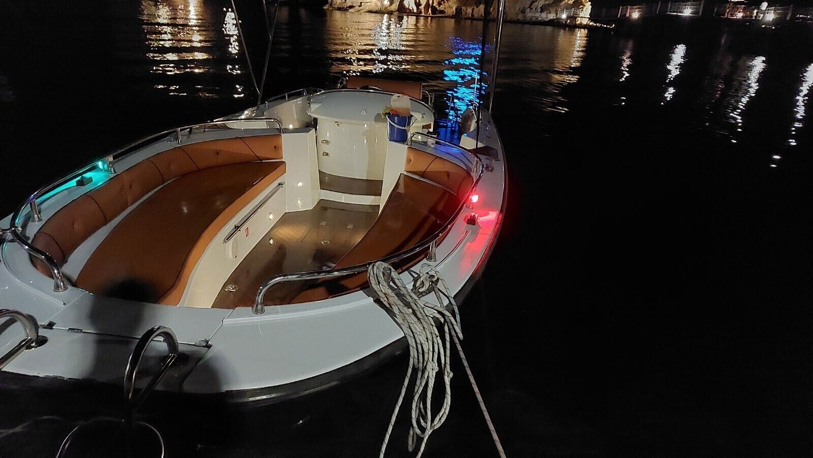 A boat with a wooden interior, metal railings, and a rope tied to the side.