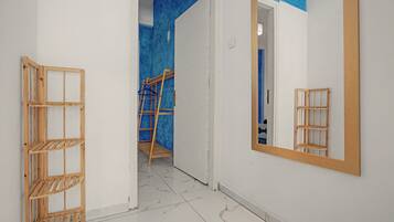 A hallway with a wooden ladder, a mirror, and a blue accent wall.