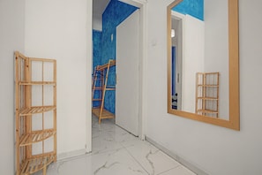 Un pasillo con una escalera de madera, un espejo y una pared azul decorativa.