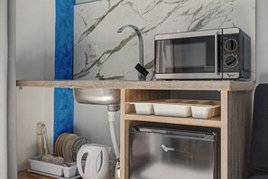 A compact kitchen with a built-in microwave, a sink, and a small refrigerator.