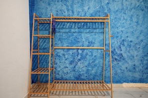 A metal shelf unit with multiple levels and a ladder, positioned against a blue textured wall.