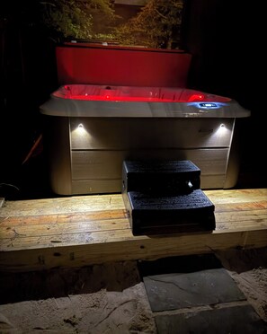 A hot tub with a wooden bench in front, surrounded by stone steps.