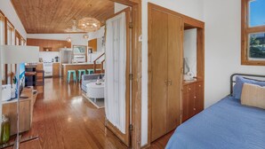 Ein Zimmer mit einem Bett, einem Holzschrank und einer Küchenzeile mit Sitzhocker.