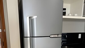 Una cocina con refrigerador de acero inoxidable, encimera negra y armarios blancos.