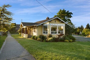Ein eingeschossiges Haus mit Veranda, Garage und gepflegtem Rasen.