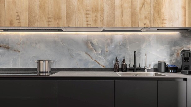 Eine moderne Küche mit Holzschränken, einer Marmor-Spritzschutzwand und Edelstahlgeräten.