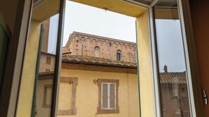 Blick aus dem Fenster auf ein Gebäude mit Ziegelaußenwand und Ziegeldach.